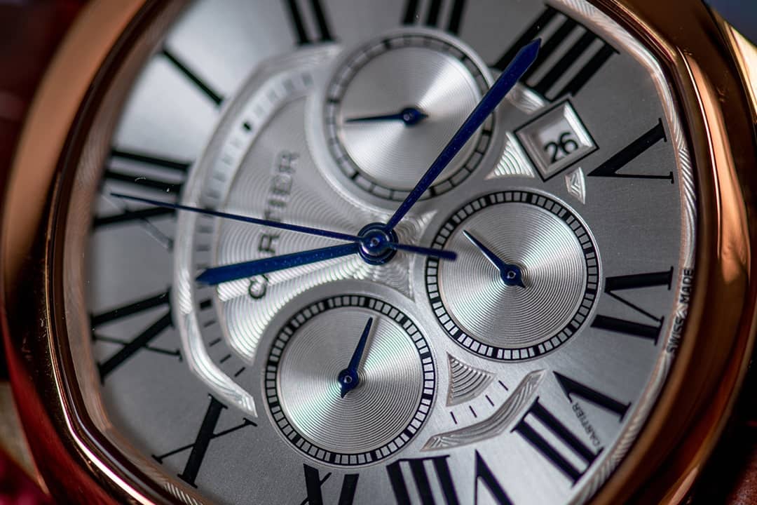 A close-up of a Cartier Drive de Cartier men's watch dial in golden steel color.